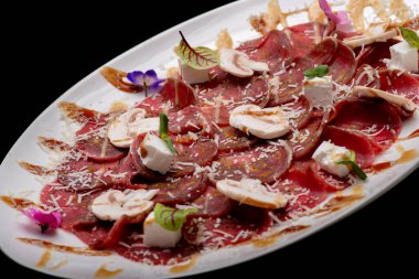 Parmesan peynirli taze et carpaccio ve beyaz tabakta roka.