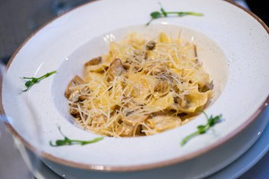 Parmesanlı ravioli ve beyaz tabakta mantar, yakın plan.