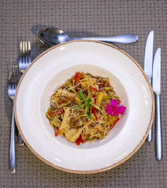 Beyaz tabakta biberiyeli kızarmış patates ve bir peçeteyle ahşap bir masa.