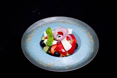 Siyah arka planda siyah tabakta taze sebzeli salata.