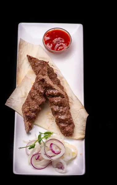 kebab on plate with onion and salad