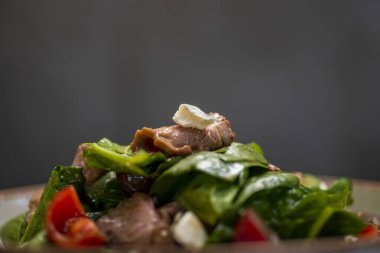 Ispanaklı ton balığı, domates ve siyah tabakta zeytin.