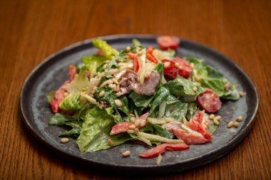 Ton balıklı salata, marul, vişneli domates ve ahşap kaplama tabakta kızarmış ekmek.