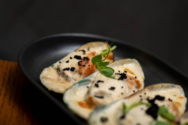 Siyah tabakta etli börekler, koyu bir arka plan.