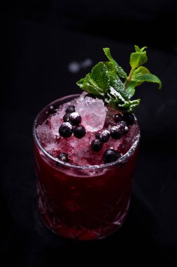 Koyu renkli böğürtlenli bir bardak taze mojito.