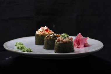 Siyah arkaplanı olan bir tabakta suşi.