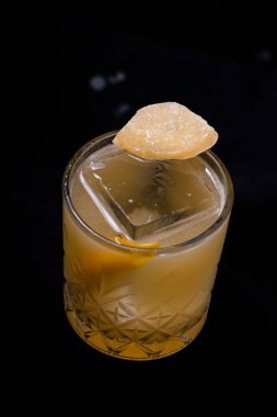 Siyah arka planda buz küpleri olan bir bardak viski.