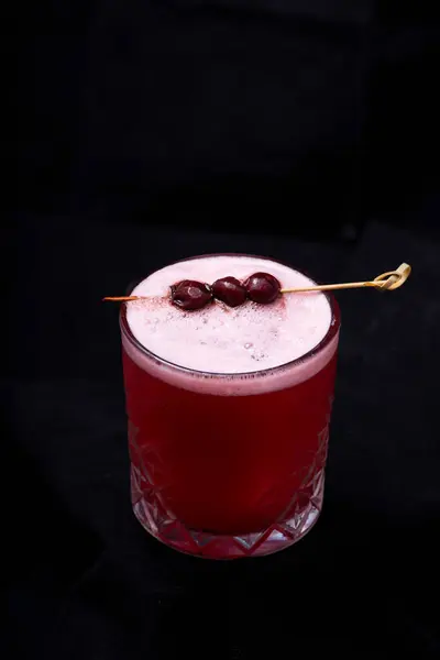cocktail with cherry on black background.
