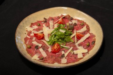 Siyah arka planda et, peynir ve fesleğenli İtalyan pacpaccio.