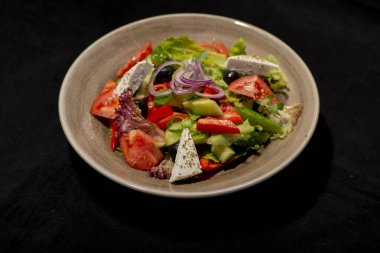 Sebzeli salata, peynir, zeytin, domates ve soğanlı siyah arkaplan