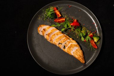 Siyah arka planda sebzeli ızgara tavuk göğsü