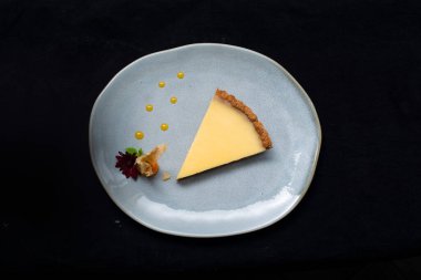 Siyah tabakta taze peynirli kek. Bir parça peynirli bir parça kek. Çatallı bir tabak. bir parça