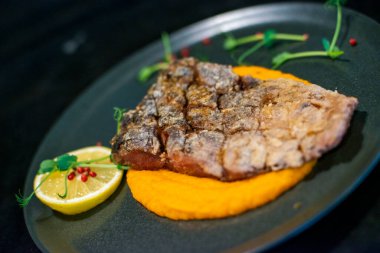 Tabakta ızgara biftek ve portakal.