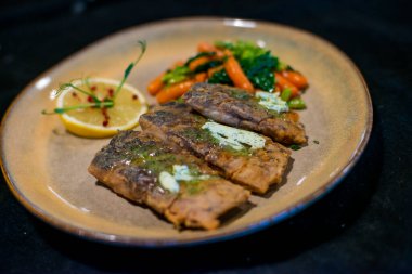 Kızarmış Balık beyaz bir tabakta sebze ile