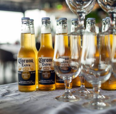 Masada bir bardak soğuk bira ve barın arka planında bir şişe bira.