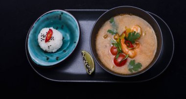 Pirinçli köri ve siyah arka planda çubukları olan siyah bir kase.