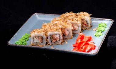 Japon suşisi siyah tabakta yuvarlanıyor.