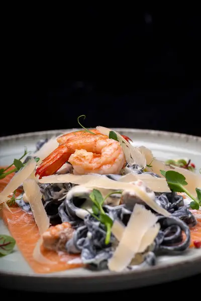 pasta with shrimp and mussels on a black plate