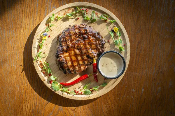 beef steak with sauce on a wooden board. top view.