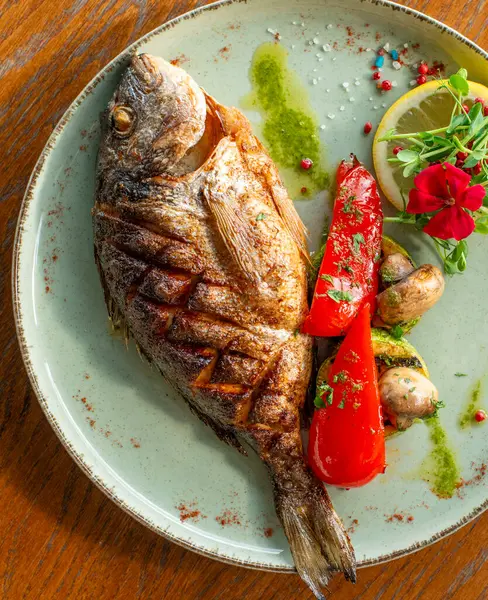 grilled fish with vegetables and herbs on white plate