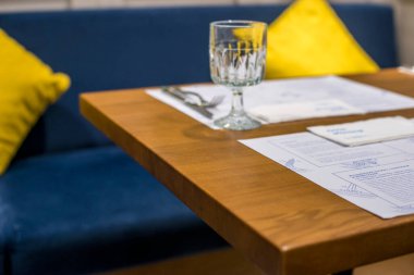 İçinde mavi bir kitap ve bir bardak su olan bir masa. Modern bir otelde..