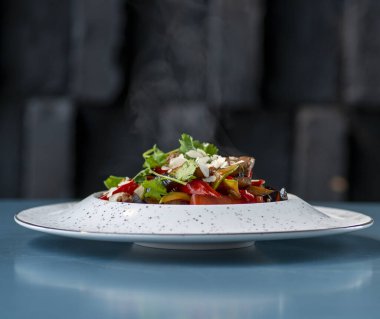 Domatesli taze salata ve siyah arka planda bir tabakta roka.