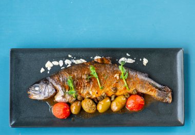 Kızarmış Dorado ve beyaz tabakta sebzeler.