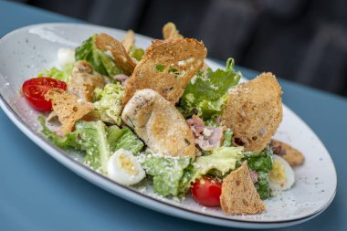 Masadaki beyaz tabakta sezar salatası.