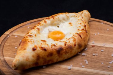 Khachapuri, siyah ahşap masada bir yumurtayla..