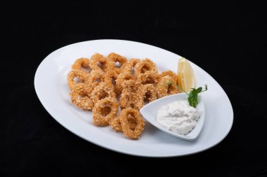 Beyaz tabakta kızarmış balık ve soğan halkaları..