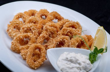 Beyaz tabakta limonlu kızarmış mürekkep balığı halkaları.