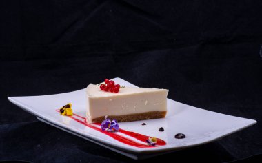 Siyah tabakta çilekli cheesecake.