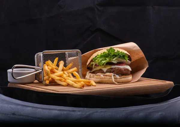 french sandwich with beef, lettuce, cheese and sauce on black wooden board.