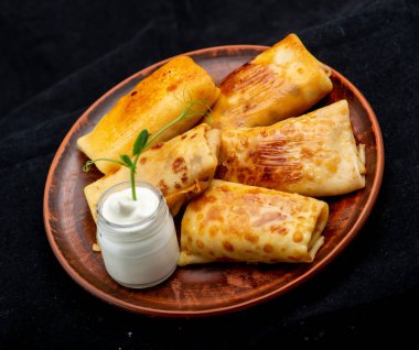 Siyah arka planda etli ve sebzeli gözleme.