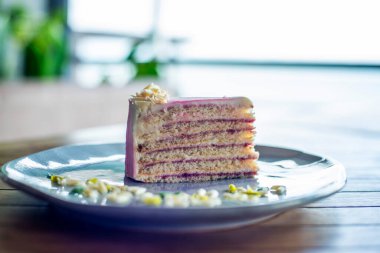 Beyaz bir masanın üzerinde pembe kremalı bir dilim pasta.