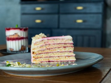 Böğürtlenli bir parça kek ve koyu ahşap bir arka planda bir fincan süt..