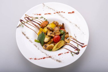 Tahta bir masada beyaz bir tabakta kızarmış sebzeler.