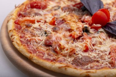 Salamlı, domatesli, mantarlı, peynirli, fesleğenli ve mantarlı lezzetli pizza.