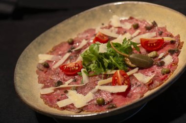 İtalyan yemeği ve siyah tabakta biftek ve fesleğen.