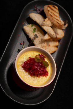 Lezzetli bir tostun dikey çekimi. Siyah arka planda bir tabak peynirli.