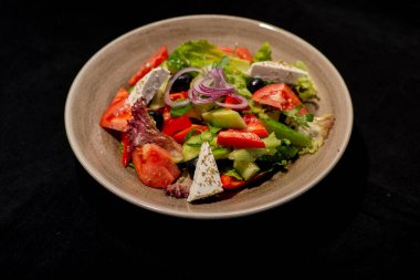 Sebzeli taze salata ve koyu arkaplanda peynir.