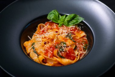 Domatesli İtalyan spagettisi ve siyah tabakta peynir.