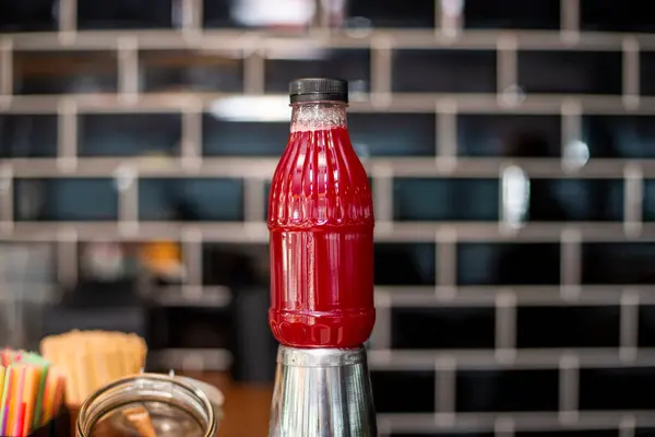 red ketchup bottle with tomato sauce and spices on wooden table in kitchen