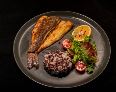 Sebzeli ızgara somon ve siyah arka planda kızarmış patates.