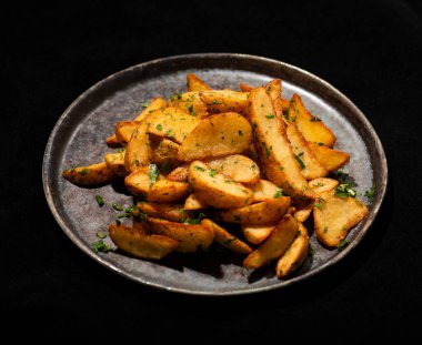 sarımsaklı fırında patates ve bir tabakta bitki.