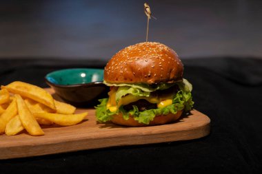 Siyah arka planda patates kızartmalı hamburger.