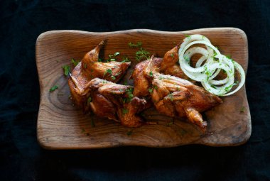 Siyah tabakta kızarmış tavuk bacağı.