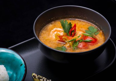 Tom yer elması çorbası, siyah tabakta, siyah arka planda, yakın plan.