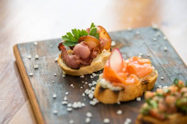 Somon füme kanepeler, krem peynir ve ahşap tabakta deniz ürünleri.