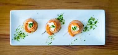 Somon, peynir ve krem peynirli börekler beyaz tabakta.